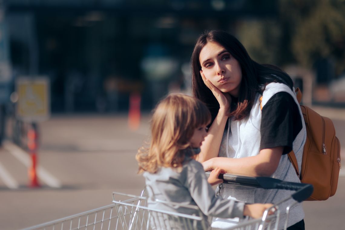 Mom looks worried pushing daughter in grocery cart