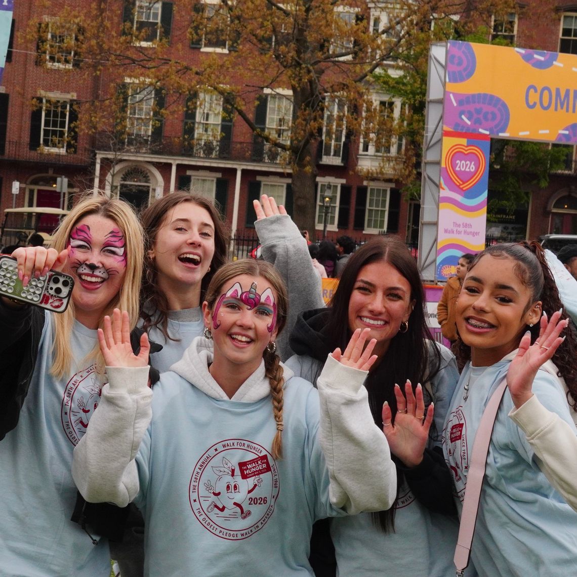 six smiling girls wave at the camera