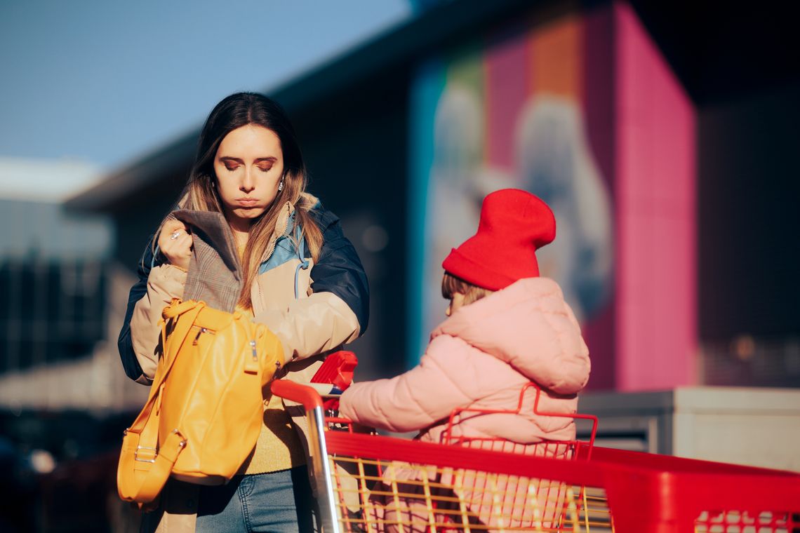 women in a parking lot with child in a grocery carriage